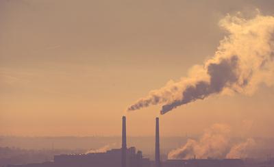 Smoking factory chimneys in morning backlit by rising sun-stock-photo