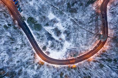 aerial view of curvy road with snowy forest-stock-foto