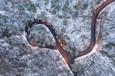 aerial view of curvy road with snowy forest-stock-photo