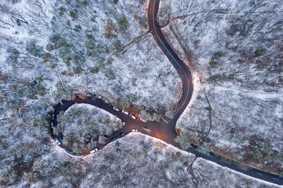 aerial view of curvy road with snowy forest-stock-photo