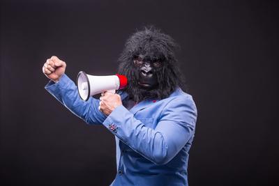 businessman wearing gorilla mask and screaming to megafon-stock-foto