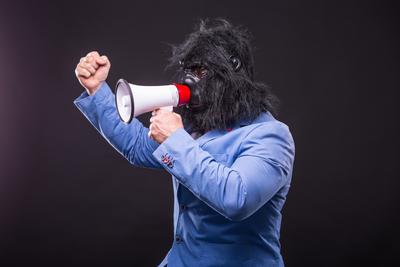 businessman wearing gorilla mask and screaming to megafon-stock-foto