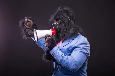 businessman wearing gorilla mask and screaming to megafon-stock-foto