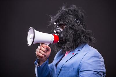 businessman wearing gorilla mask and screaming to megafon-stock-foto