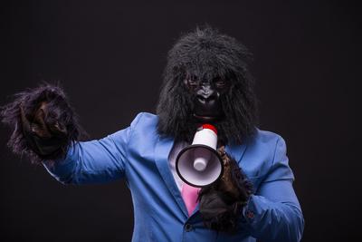 businessman wearing gorilla mask and screaming to megafon-stock-foto