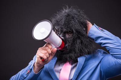 businessman wearing gorilla mask and screaming to megafon-stock-foto