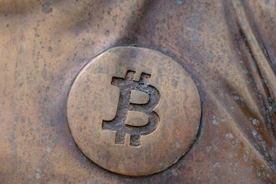 a bitcoin icon on a bronze statue-stock-photo