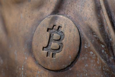 a bitcoin icon on a bronze statue-stock-photo