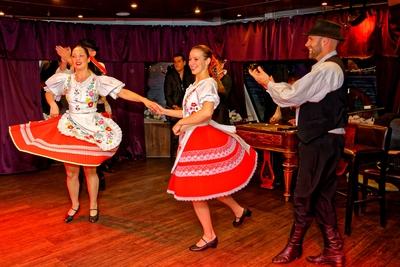 Magyar folklor, népi tánc együttes, két lány táncol magyar öltözékben, férfi tapsol nekik-stock-photo