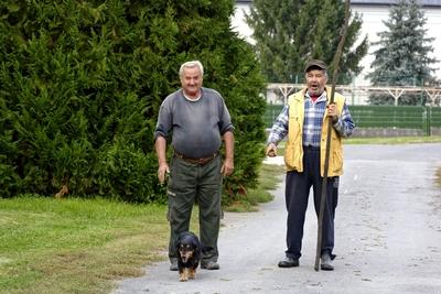 Két igazi szatmári férfi egy tacskóval az utcán, Panyolában-stock-foto