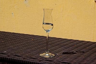 Egy pohár pálinka egy fonott asztalon sárga házfal elõtt-stock-foto