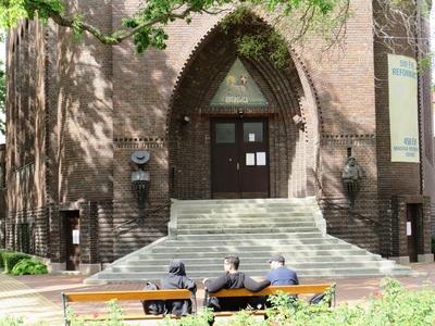 People sitting on a bench in font of the reformed church - Szeged-stock-photo