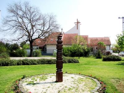 Gyál, 2010. április 24.A gyáli 1848-as és 1956-os szabadságharcnak emléket állító kopjafa. Mögötte az első gyáli templom, melyet Szilvási Sándor plébános alakított templommá bálteremből 1948-ban.-stock-foto