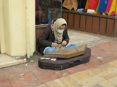 An Iranian woman strumming a zither in front of the Grand Bazaar in Tehran-stock-photo