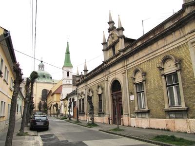 V?c, 2016. m?rcius 27.A Gasparik K?zm?r utca. Jobbra a 8. sz. alatti, 1900-as ?vek elej?n ?p?lt v?dett lak??p?let. Jobbra fentebb a Karolina k?polna tornya. Szemben a v?ci sz?kesegyh?z kupol?ja. Balra parkol? aut?.-stock-foto