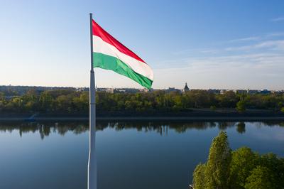 Hungary Budapest. Wind waving a  Hungarian flag. There is the Margit island on the background. Clear sky still river.-stock-photo
