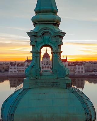 Unique photo about the Hungarian Parliament building through a church belltower. Amazing morning mood.-stock-photo