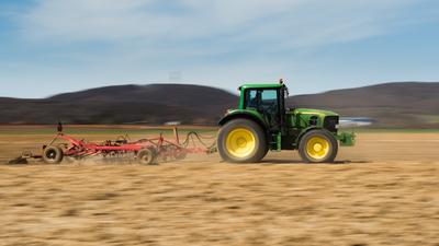 A farmer plowing with a John Deere tractor. Sunny day on the field.-stock-foto