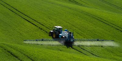 A farmer spraying on the spring wheat field with a John Deere tractor and a mamut topline sprayer.-stock-photo