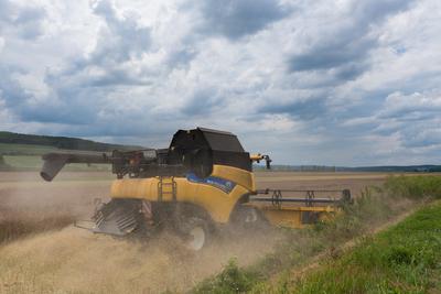 Farmers are harvesting with a New Holland CR9080 combine on a cloudy day.-stock-photo