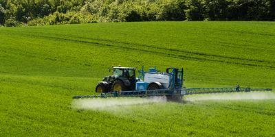 A farmer spraying on the spring wheat field with a John Deere tractor and a mamut topline sprayer.-stock-photo