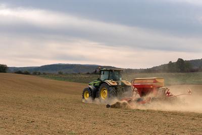 A farmer sowing with a John Deere tractor and a Horsch Pronto 4dc seeding machine.-stock-photo