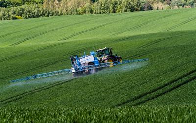 A farmer spraying on the spring wheat field with a John Deere tractor and a mamut topline sprayer.-stock-photo