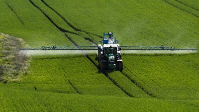 A farmer spraying on the spring wheat field with a John Deere tractor and a mamut topline sprayer.-stock-foto