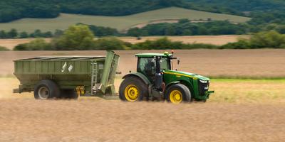 The farmer is going with a John Deere 8335R tractor and a Fliegl ULW trailer to load the harvested seeds.-stock-photo