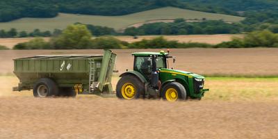 The farmer is going with a John Deere 8335R tractor and a Fliegl ULW trailer to load the harvested seeds.-stock-foto