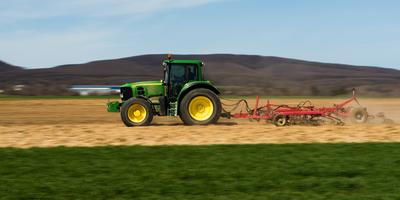 A farmer is plowing with a John Deere tractor. Sunny day on the field. It's a panning shot, that cause the blurry background and foreground.-stock-foto