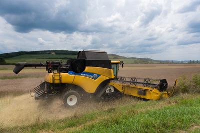 Farmers are harvesting with a New Holland CR9080 combine on a cloudy day.-stock-photo