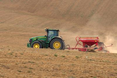 A farmer sowing with a John Deere tractor and a Horsch Pronto 4dc seeding machine. It's a panning shot, that cause the blurry background.-stock-photo