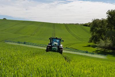 A farmer spraying on the spring wheat field with a John Deere tractor and a mamut topline sprayer.-stock-foto