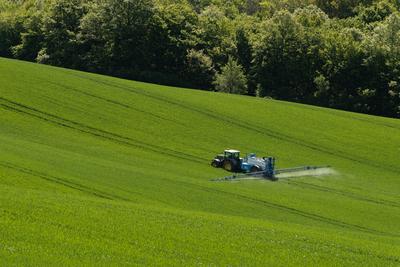 A farmer spraying on the spring wheat field with a John Deere tractor and a mamut topline sprayer.-stock-foto