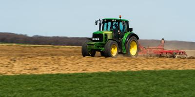A farmer is plowing with a John Deere tractor. Sunny day on the field. It's a panning shot, that cause the blurry background and foreground.-stock-foto