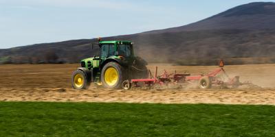 A farmer is plowing with a John Deere tractor. Sunny day on the field. It's a panning shot, that cause the blurry background and foreground.-stock-foto
