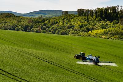 A farmer spraying on the spring wheat field with a John Deere tractor and a mamut topline sprayer.-stock-foto