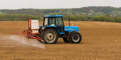A farmer spraying with a Landini Evolution 9880 tractor. It's a panning shot, that's cause the blurry in the back and foreground.-stock-photo