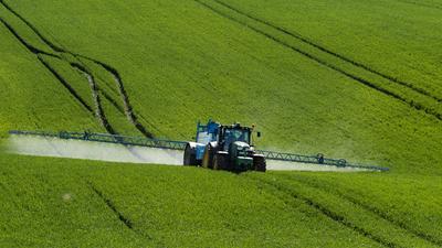 A farmer spraying on the spring wheat field with a John Deere tractor and a mamut topline sprayer.-stock-photo