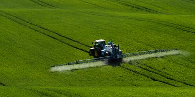 A farmer spraying on the spring wheat field with a John Deere tractor and a mamut topline sprayer.-stock-foto