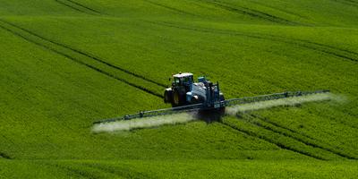 A farmer spraying on the spring wheat field with a John Deere tractor and a mamut topline sprayer.-stock-photo