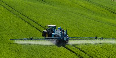 A farmer spraying on the spring wheat field with a John Deere tractor and a mamut topline sprayer.-stock-foto