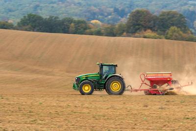 A farmer sowing with a John Deere tractor and a Horsch Pronto 4dc seeding machine. It's a panning shot, that cause the blurry background.-stock-foto