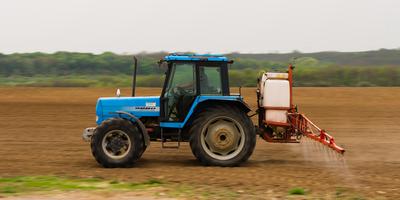 A farmer spraying with a Landini Evolution 9880 tractor. It's a panning shot, that's cause the blurry in the back and foreground.-stock-photo