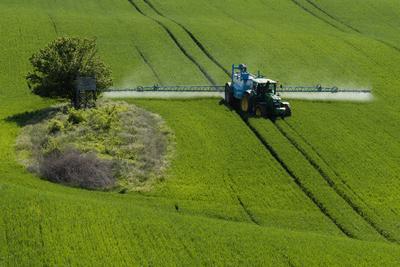 A farmer spraying on the spring wheat field with a John Deere tractor and a mamut topline sprayer.-stock-foto