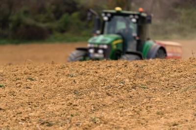 A farmer sowing in the background with a John Deere tractor and a Horsch Pronto 4dc seeding machine.-stock-photo