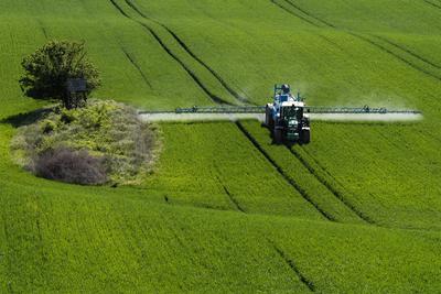 A farmer spraying on the spring wheat field with a John Deere tractor and a mamut topline sprayer.-stock-foto