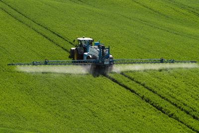 A farmer spraying on the spring wheat field with a John Deere tractor and a mamut topline sprayer.-stock-foto