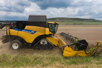 Farmers are harvesting with a New Holland CR9080 combine on a cloudy day.-stock-photo